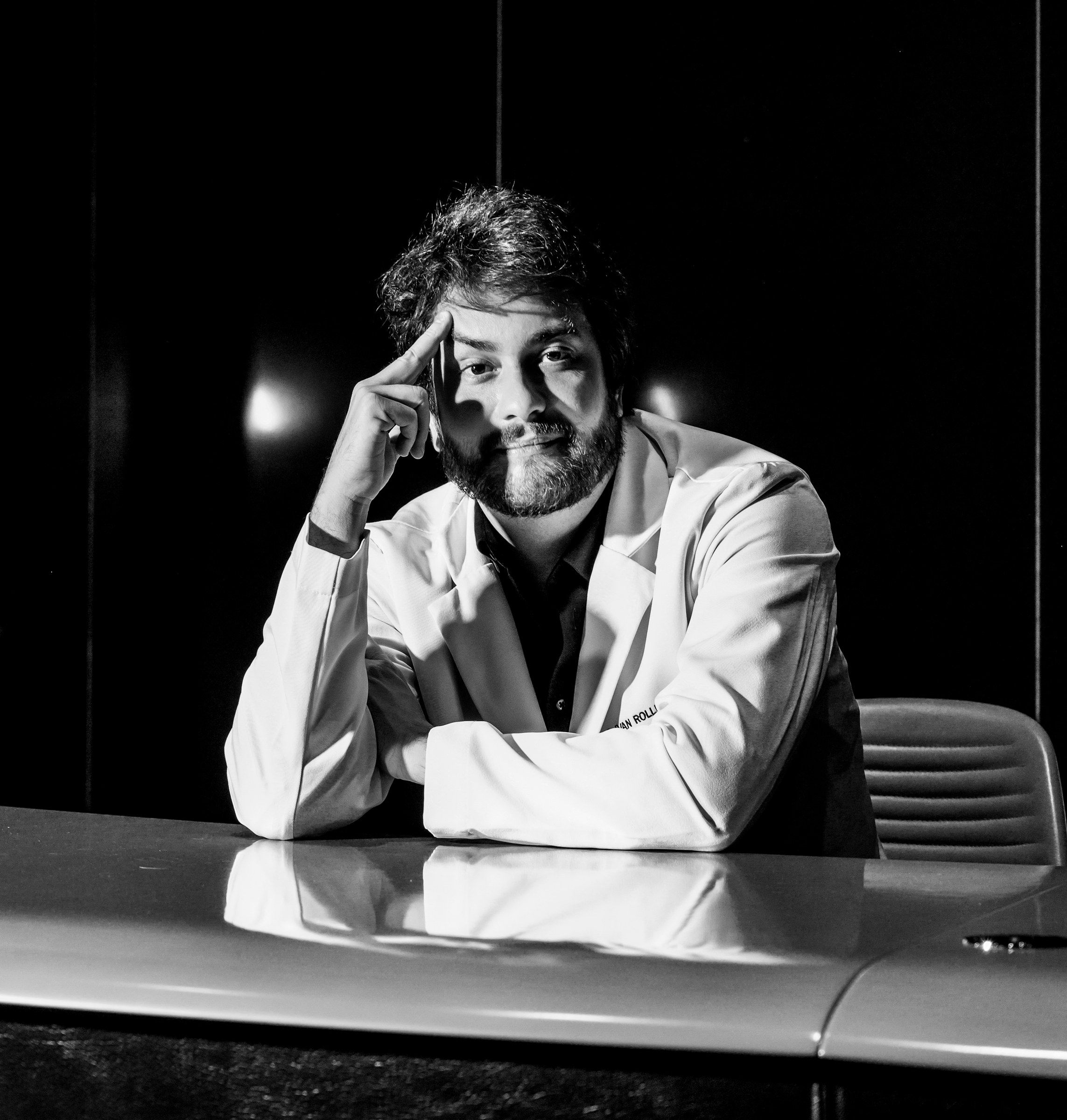 Dr. Ivan Rollemberg em retrato em preto e branco, sentado à mesa, com a mão apoiada na têmpora